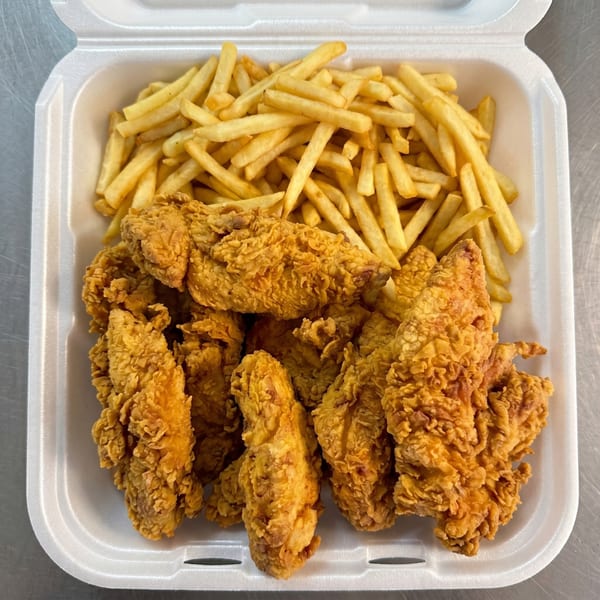 Crispy fried chicken tenders and golden french fries in a white takeout container.