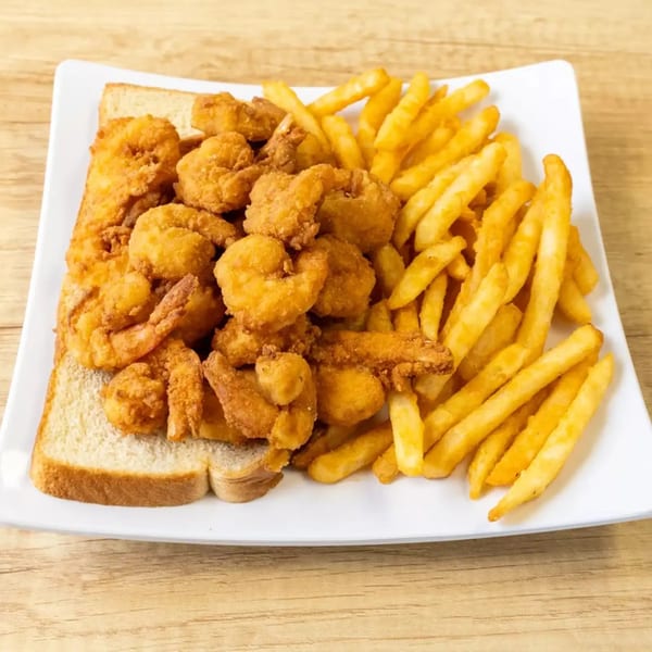 A white plate holds golden fried shrimp on white bread with a side of french fries.